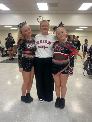 Two young cheerleaders with their smiling coach.