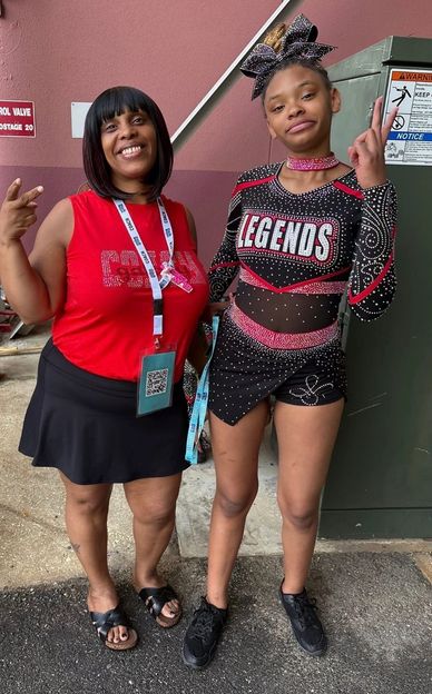 Two women posing confidently, one in cheerleading outfit.