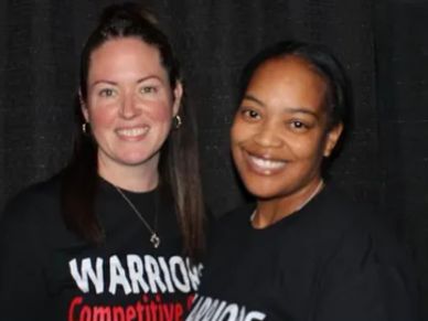 Two smiling women wearing matching black shirts.