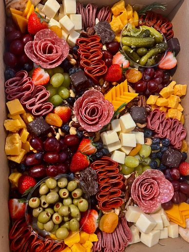 A colorful charcuterie board with meats, cheeses, fruits, and olives.