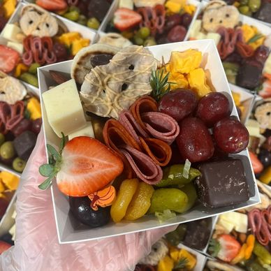 A colorful charcuterie box with fruits, cheese, and meats.