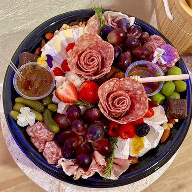 Elegant charcuterie board with salami roses, fruits, cheese, and accompaniments.
