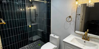 Modern bathroom with black tile shower and white vanity.