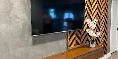 Modern living room wall with TV and wooden decor.