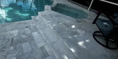 Poolside area with white tiled floor and steps.
