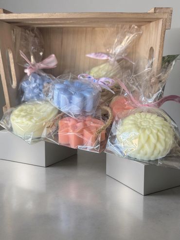 Colorful floral soaps wrapped in plastic inside a wooden crate.
