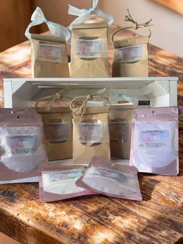 Variety of soothing bath salts in brown and pink packaging displayed on a wooden table.