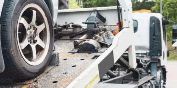 Close-up of a car tire loaded on a flatbed tow truck.
