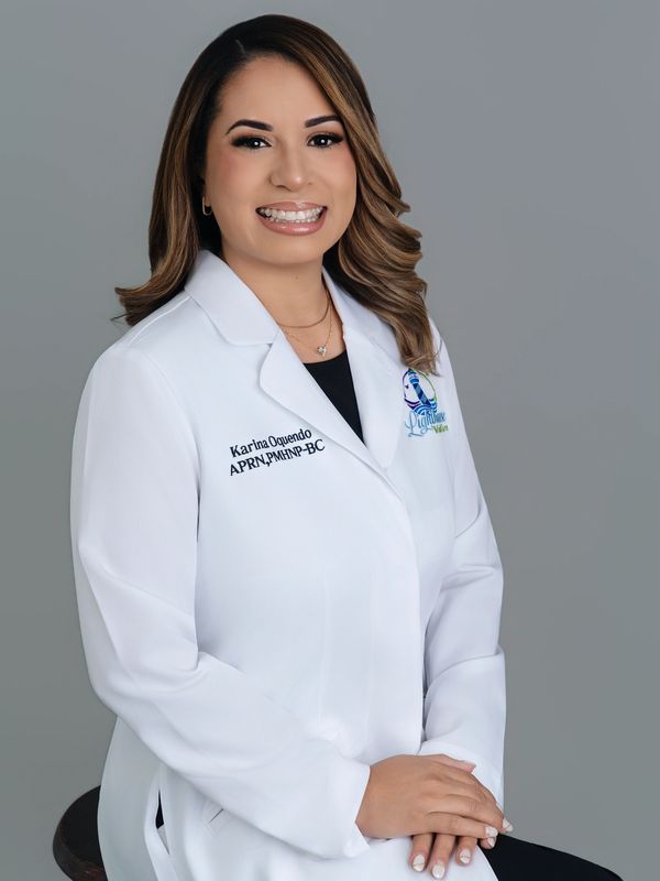 Professional portrait of a smiling female healthcare provider in a white coat.