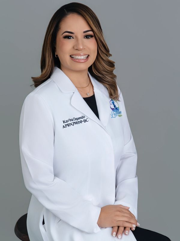 Professional portrait of a smiling female healthcare provider in a white coat.