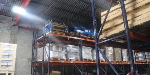 Industrial warehouse shelves stocked with pallets and wrapped goods.