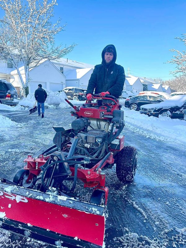 Person using a snowplow on a residential street.