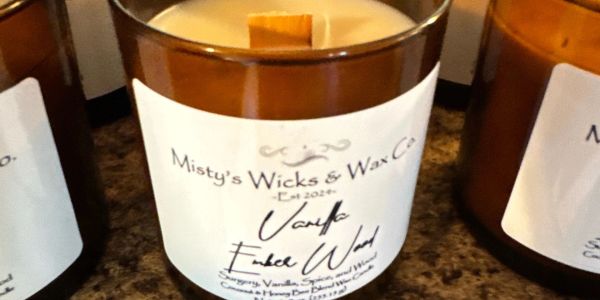 Brown glass candles labeled "Misty's Wicks & Wax Co." on a countertop.
