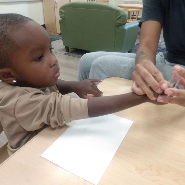 A young child receiving a hand treatment or care from an adult.