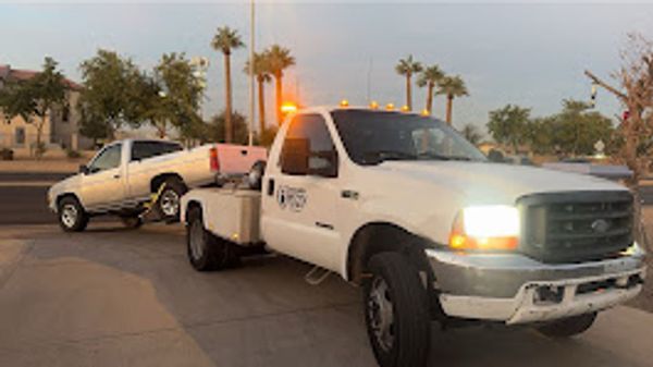 Three white pickup trucks parked side by side at dusk.
