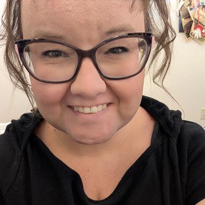 Smiling woman with glasses and a black top.