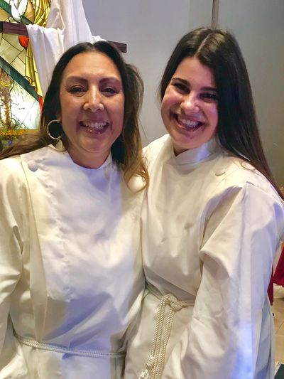 Two women smiling in white religious robes.