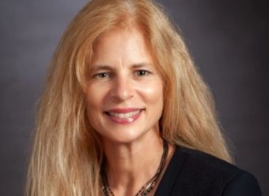 Professional portrait of a smiling woman with long blonde hair.