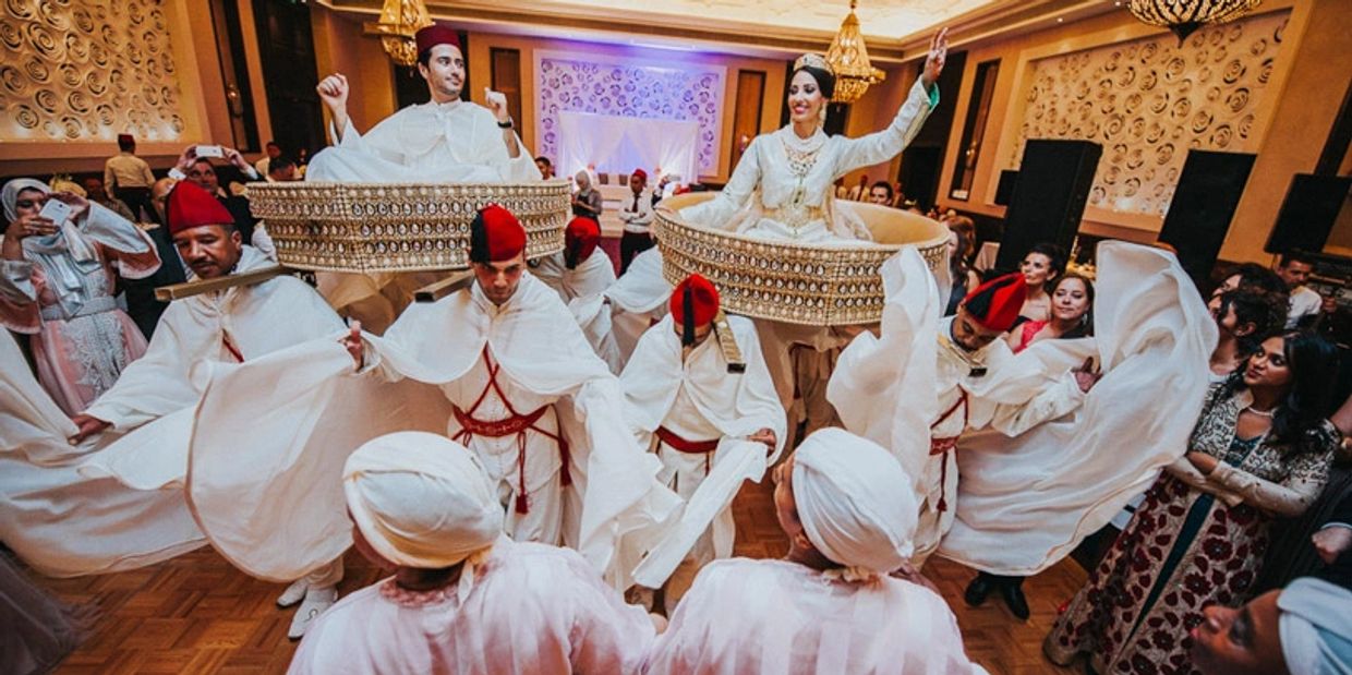 Traditional Moroccan wedding dance with dancers and elevated bride and groom.