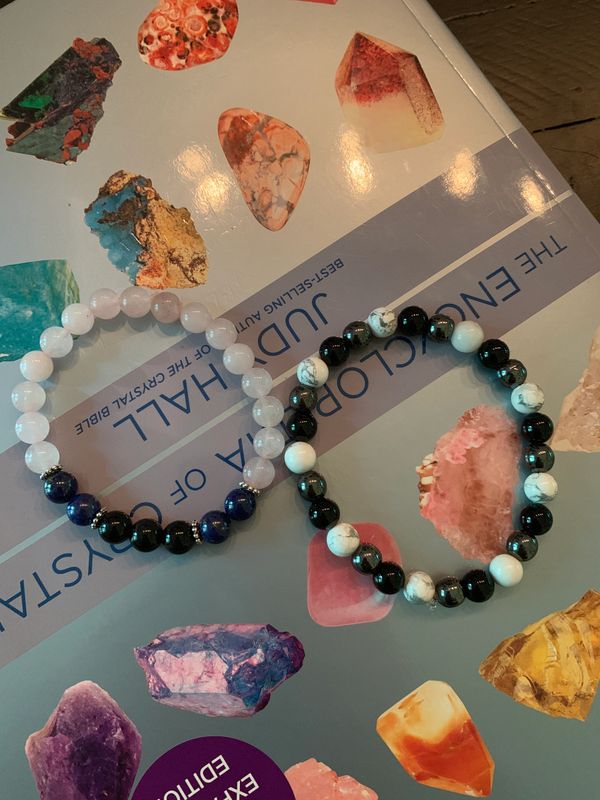 Two beaded bracelets on a colorful crystal guidebook.