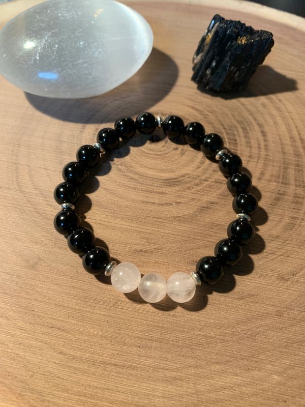 Black and white beaded bracelet on wooden surface with crystal stones.
