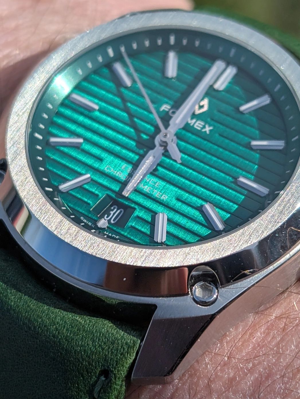 Close-up of a Formex watch with a green textured dial and stainless steel case.