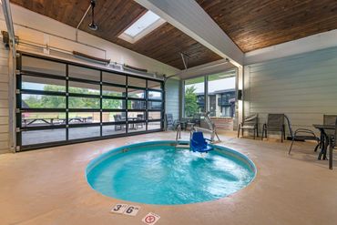 Indoor jacuzzi with seating and a view of the outdoor patio area.