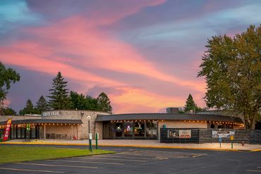 Exterior of Grey Fox restaurant during a vibrant sunset with parking lot in front.