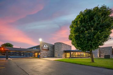 Fairway Inn & Suites building at sunset with a large tree in the foreground.