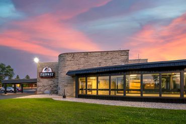 Fairway Inn & Suites building at sunset with colorful sky.