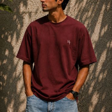 Man in maroon t-shirt and blue jeans with hands in pockets.