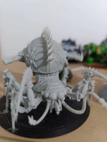 Unpainted spiky insect-like miniature on a black base.