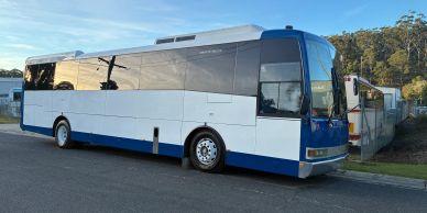 White and blue bus parked on the side of the road.