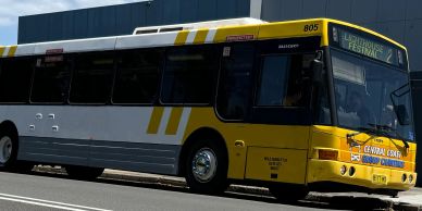 Yellow and white city bus parked on the street.