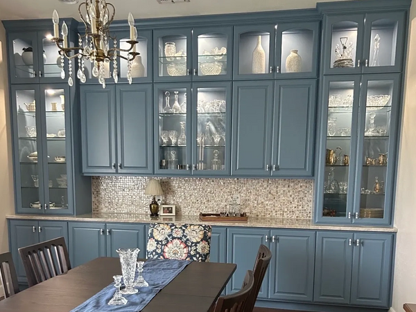 Elegant dining room with blue cabinets, crystal decor, and a chandelier.