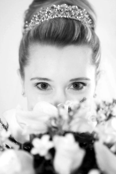 up-close bride peeking behind a flower bouquet