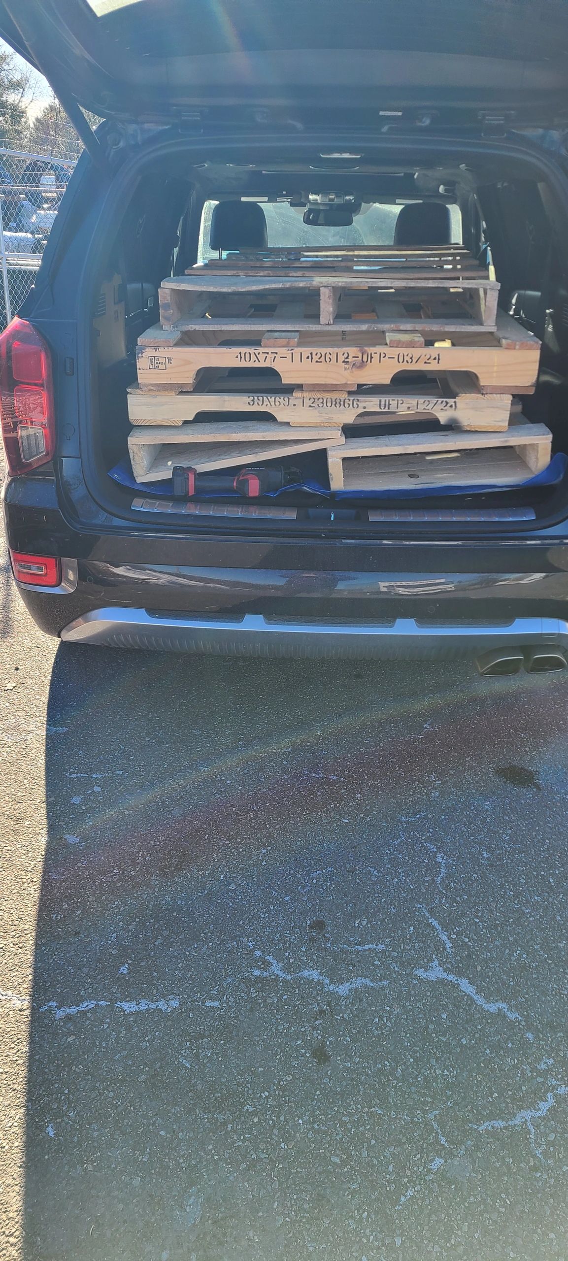 Wooden pallets loaded in the back of a dark SUV.