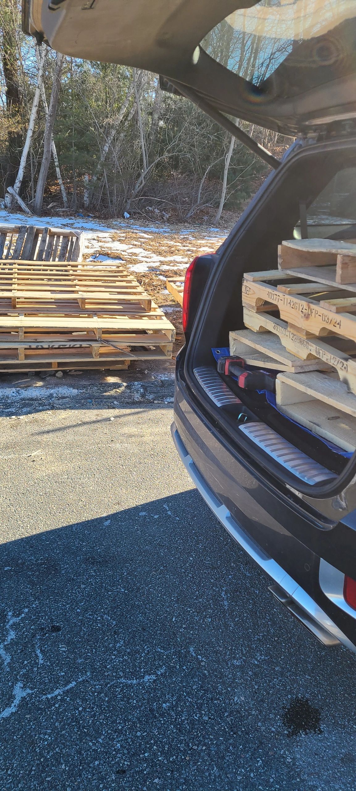 Car trunk loaded with wooden pallets.