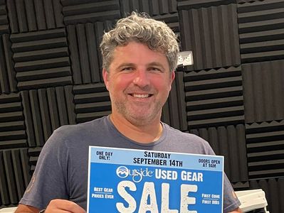 Man holding a flyer for an Outside Used Gear Sale on September 14th.