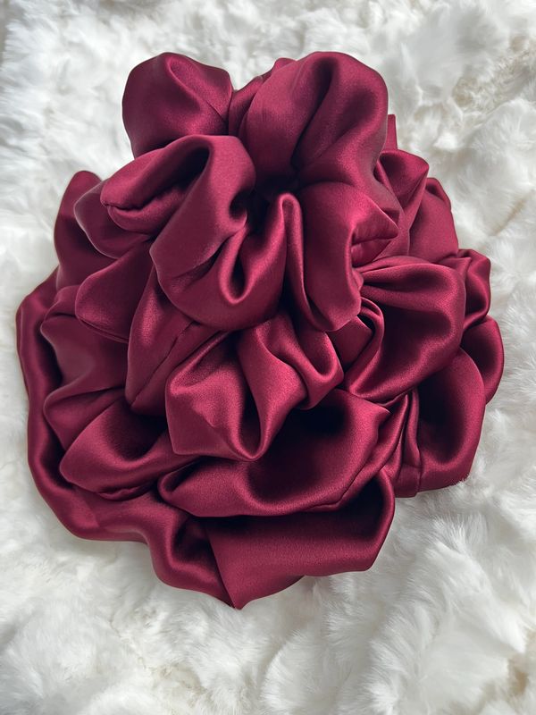 Luxurious maroon satin scrunchie on a soft white fur background.