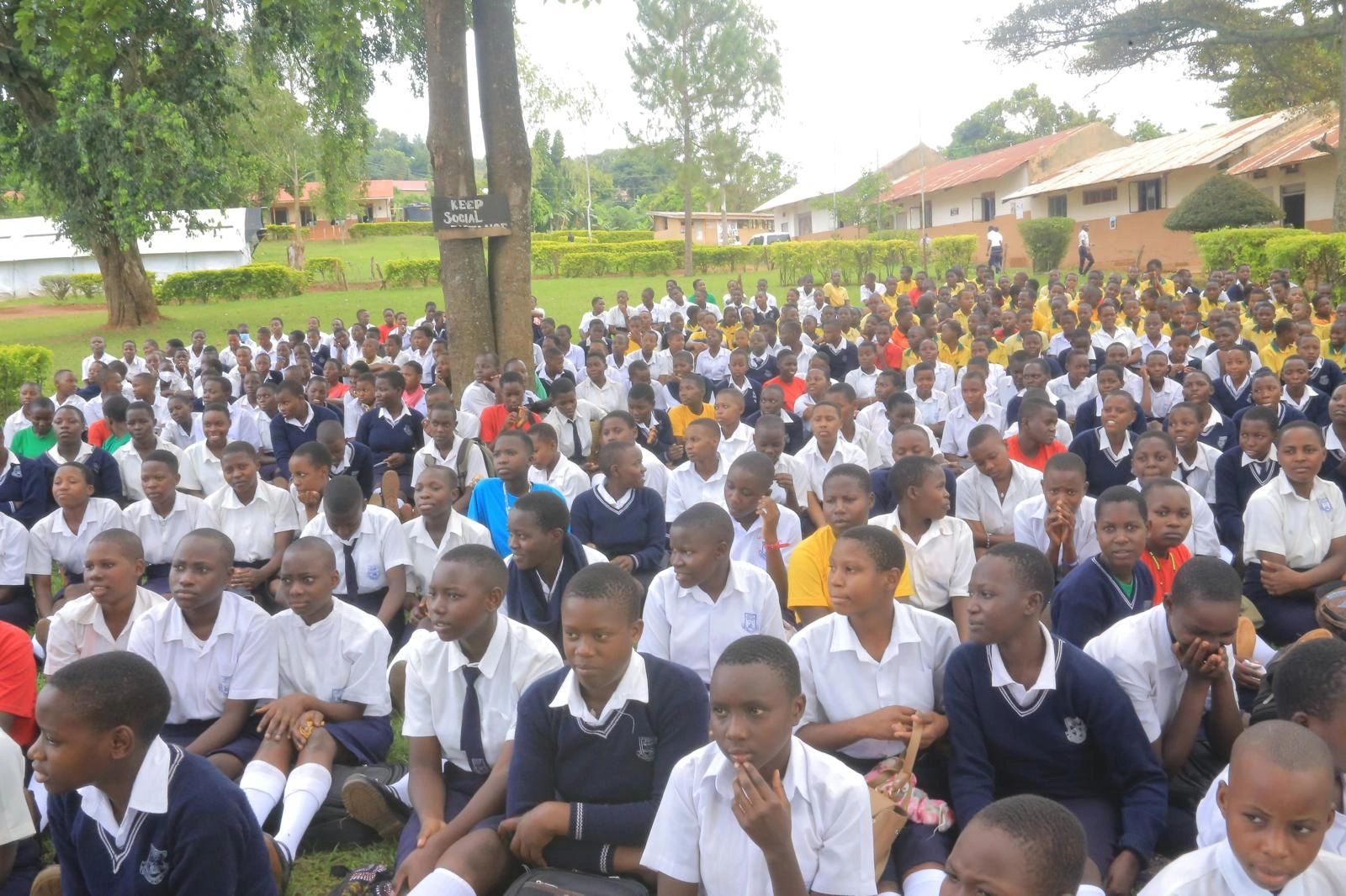 Large group of students seated outdoors in school uniforms.