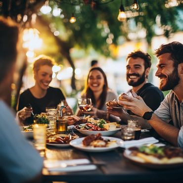 Friends enjoying a joyful outdoor dinner with warm lighting.