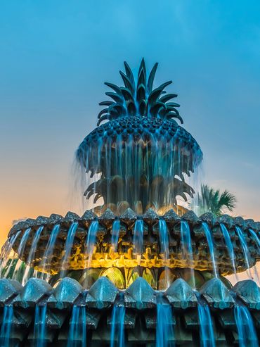Ornate pineapple-shaped fountain flowing water at sunset.