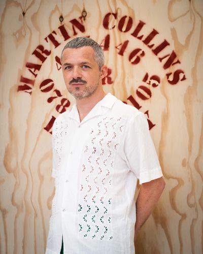 Elliott Flanagan photographed in front of a wooden 'Martin Collins' window shuttering board.