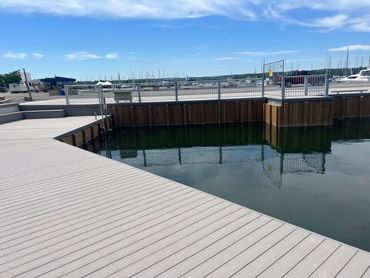 Empty wooden dock area by calm water under a clear blue sky.