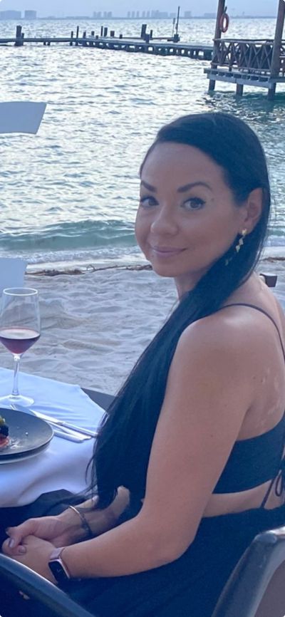 Woman sitting at a beachside table with a glass of wine.
