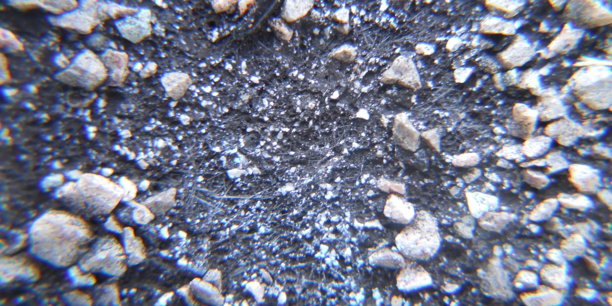 Close-up of a rocky surface with small stones and fine spider webs.