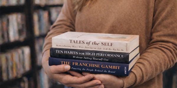 Person holding three books on self-improvement and business strategies.