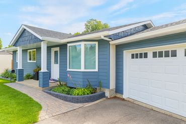 Blue suburban house with a well-maintained front yard and attached garage.