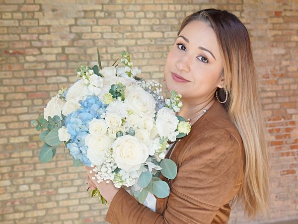 Woman holding a bouquet of white and blue flowers.